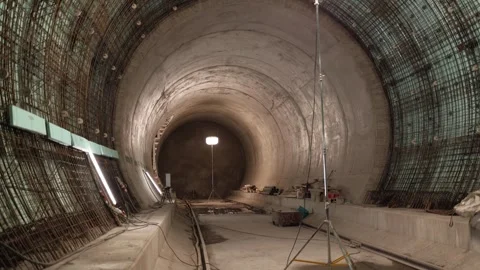 Concrete tunnel under construction with exposed rebar and scattered tools illumi Stock Footage 309657273