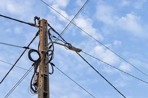 A concrete utility pole featuring a modern LED streetlight and a messy tangle Stock Photos