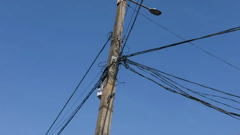 Concrete utility pole holding tangled communication cables under clear blue sky. Stock Footage 331861006