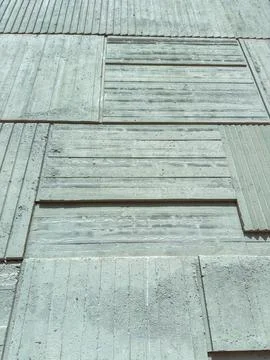 The concrete wall displays various textures and shapes of panels under sunlig Stock Photos