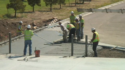 Concrete workers hustle to level and smooth newly poured cement mix. Stock Footage 139147