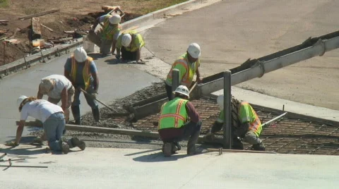 Concrete workers spread and flatten newly poured cement mix. Stock Footage 139041