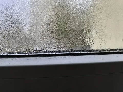 Condensation on the window forms droplets flowing on the glass Stock Photos