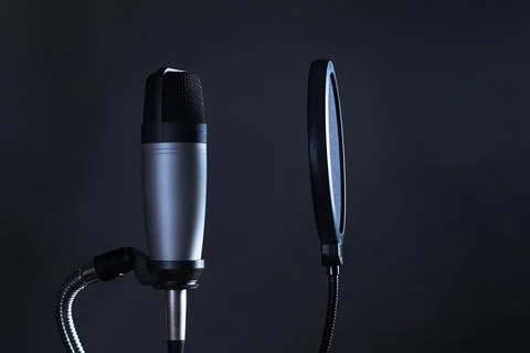 Condenser microphone with pop filter isolated on dark background. Stock Photos