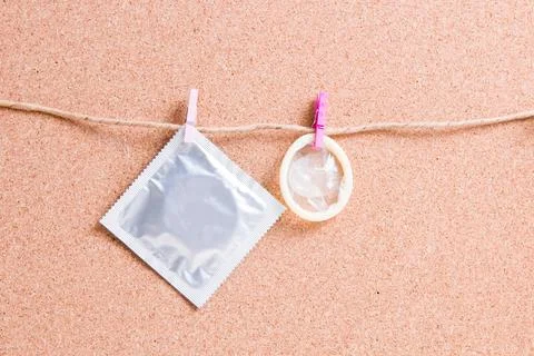 Condom and packaging hang on small wooden clothespins on a paper thread again Stock Photos