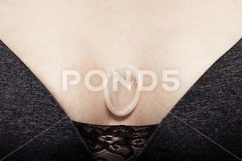 Condom in girl hand on boobs brassiere. Safe sex concept Stock Photos