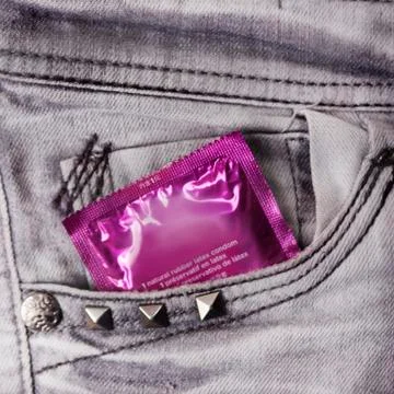 Condom in the grey jeans Stock Photos