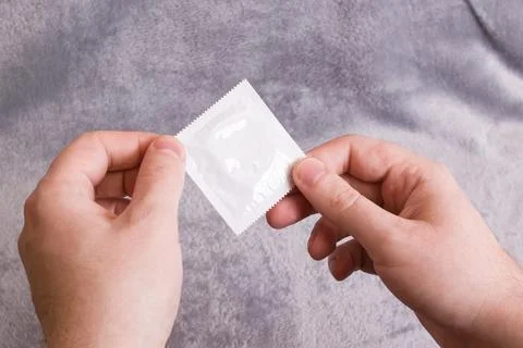 Condom in hand on a gray background Stock Photos