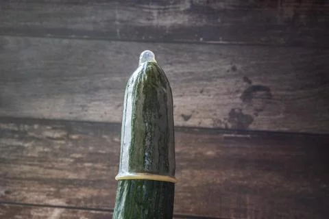 A condom is pulled over a green cucumber 库存照片