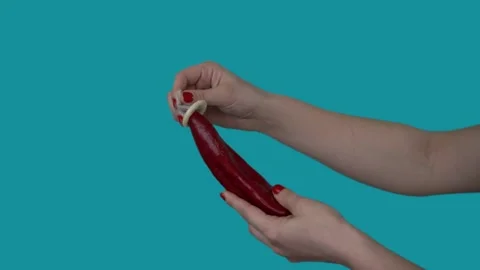 A condom is put on a big red pepper. 4k Close-up. Blue background 스톡 동영상 131112668