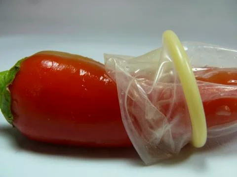 Condom on red chilli Stock Photos