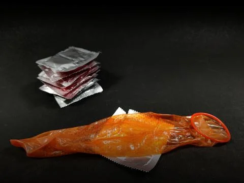Condom stretch open placed on packets on textured black background with copy 스톡 사진