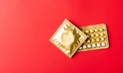 Condom on wrapper pack and contraceptive pills blister hormonal birth control Stock Photos
