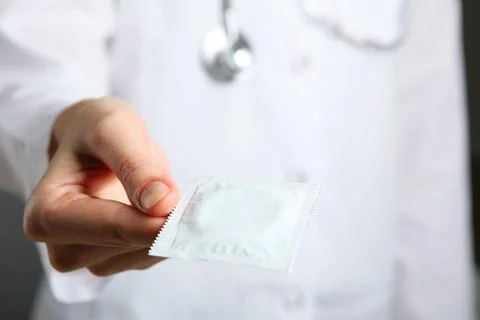 Condoms in the hands of a doctor in a white coat Stock Photos
