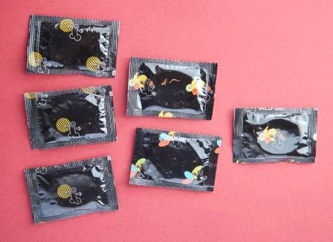 Condoms on red background with copy space. Having safe sex Stock Photos