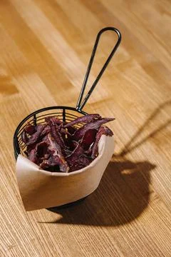 Cone of gourmet beef chips served in a stylish wire basket, perfect for a Stock Photos