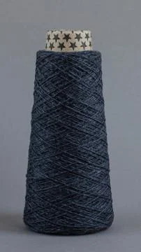 Cone of gray wool yarn on light gray background Stock Photos