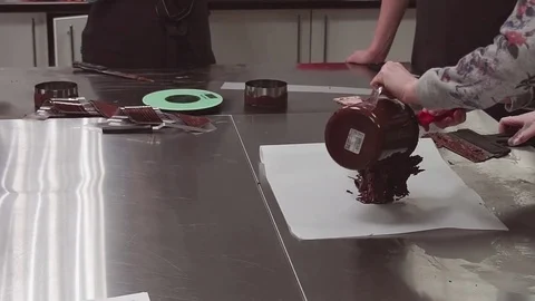 Confectioner apprentice drops melted chocolate piece on cooking paper Video stock 80069830