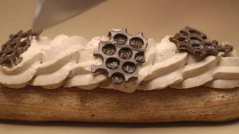 Confectioner cuts eclair in a half by knife in slow motion, dessert in cafe Stock Footage 118660846