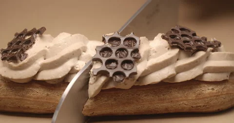 Confectioner cuts eclair in a half by knife in slow motion Stock Footage 143781623