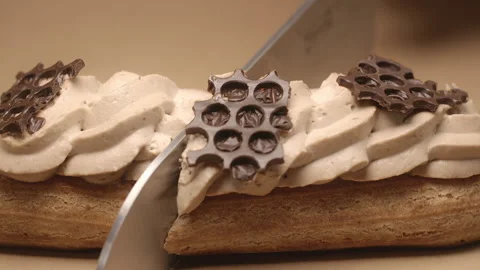 Confectioner cuts eclair in a half by knife in slow motion Stock Footage 143781681