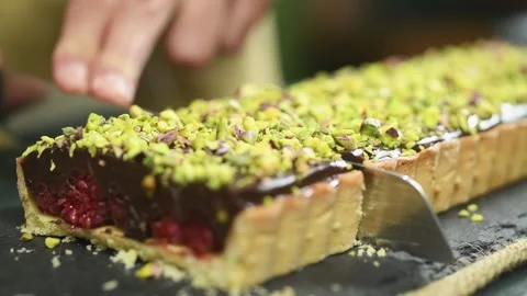 The confectioner cuts a piece of chocolate raspberry tart. Stock Footage 202072103