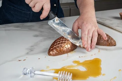 Confectioner cutting half of a chocolate Easter egg on marble. Stock Photos