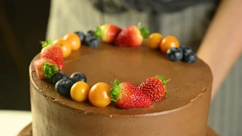 Confectioner decorates chocolate cake with fruit Stock Footage 120401385