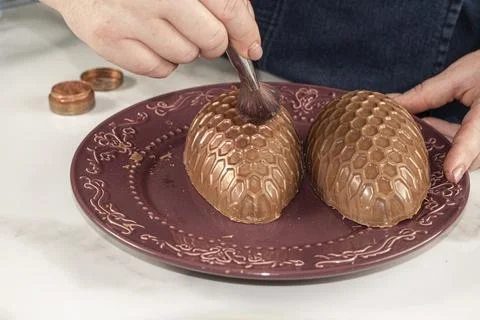 Confectioner decorating a chocolate Easter egg with a honeycomb texture with  Fotos de archivo