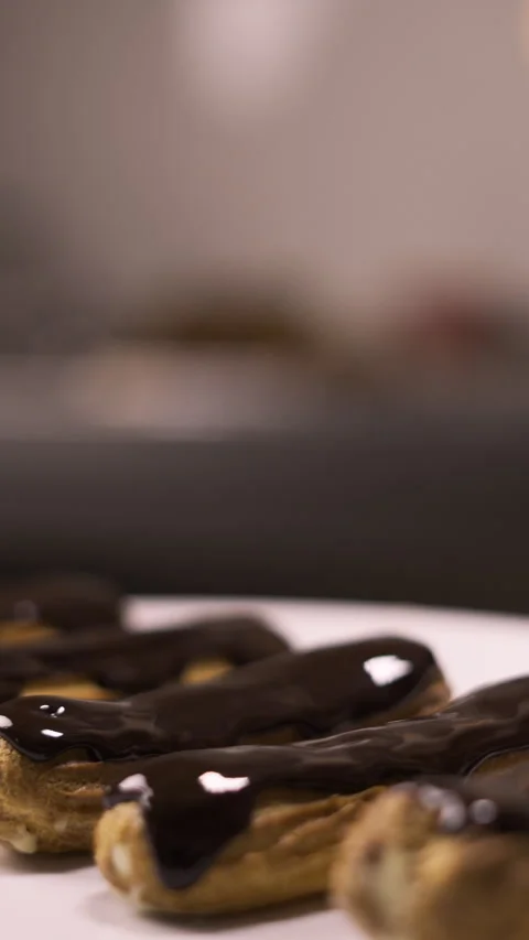 Confectioner decorating french dessert eclair with dark chocolate glaze and nuts Stock Footage 294793876