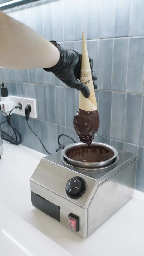 Confectioner dipping waffle cone into melted chocolate in slow motion Stock Footage 318101168