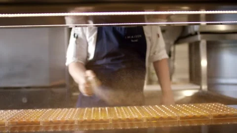 Confectioner Dusting Cocoa over Praline Tray, Behind Shop Glass, Close Up Shot Stock Footage 341341775