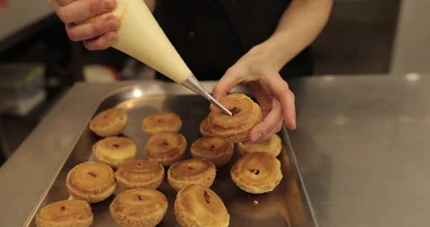 The confectioner fills the eclair with cream using a pastry syringe. Stock Footage 254816553