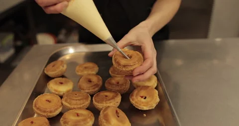 The confectioner fills the eclair with cream using a pastry syringe. Stock Footage 254816778