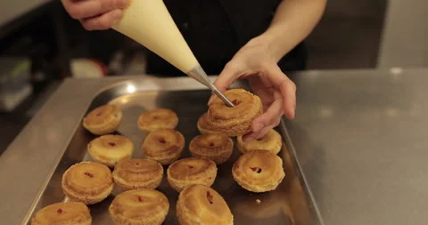 The confectioner fills the eclair with cream using a pastry syringe. Stock Footage 254817737