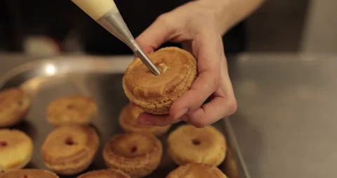 The confectioner fills the eclair with cream using a pastry syringe. Stock Footage 254817979