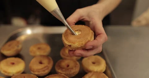The confectioner fills the eclair with cream using a pastry syringe. Stock Footage 254818300