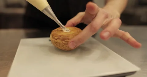 The confectioner fills the eclair with cream using a pastry syringe. Stock Footage 254818302