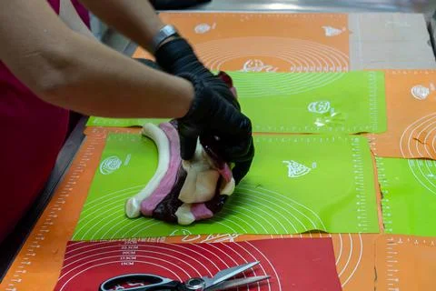 Confectioner Folding Layers of Multicolored Sugar Dough on Green Table Mat Stock-Fotos