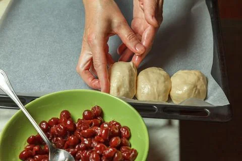 Confectioner forms buns with cherries from baking dough 스톡 사진
