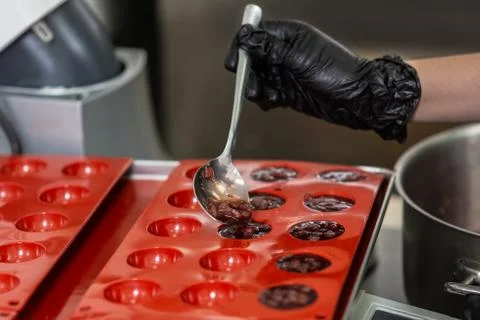 Confectioner in gloves makes chocolates in forms Stock Photos