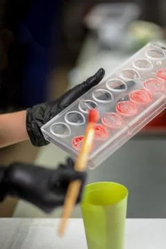 Confectioner in gloves makes chocolates in forms Stock Photos