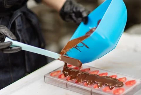 Confectioner in gloves makes chocolates in forms Stock Photos