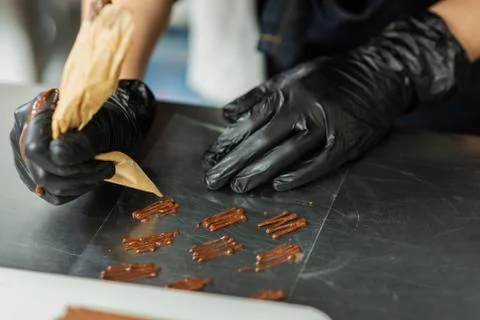 Confectioner in gloves makes chocolates in forms Stock Photos