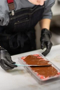 Confectioner in gloves makes chocolates in forms Stock Photos