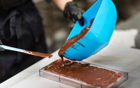 Confectioner in gloves makes chocolates in forms Stock Photos