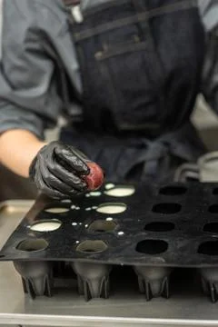 Confectioner in gloves makes chocolates in forms Stock Photos