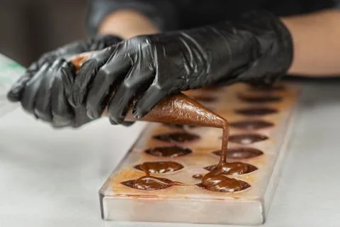 Confectioner in gloves makes chocolates in forms Stock Photos