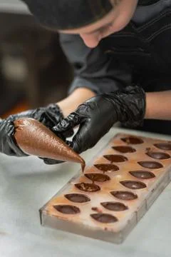 Confectioner in gloves makes chocolates in forms Stock Photos