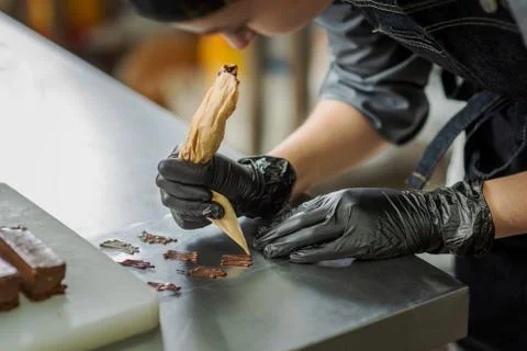 Confectioner in gloves makes chocolates in forms Stock Photos